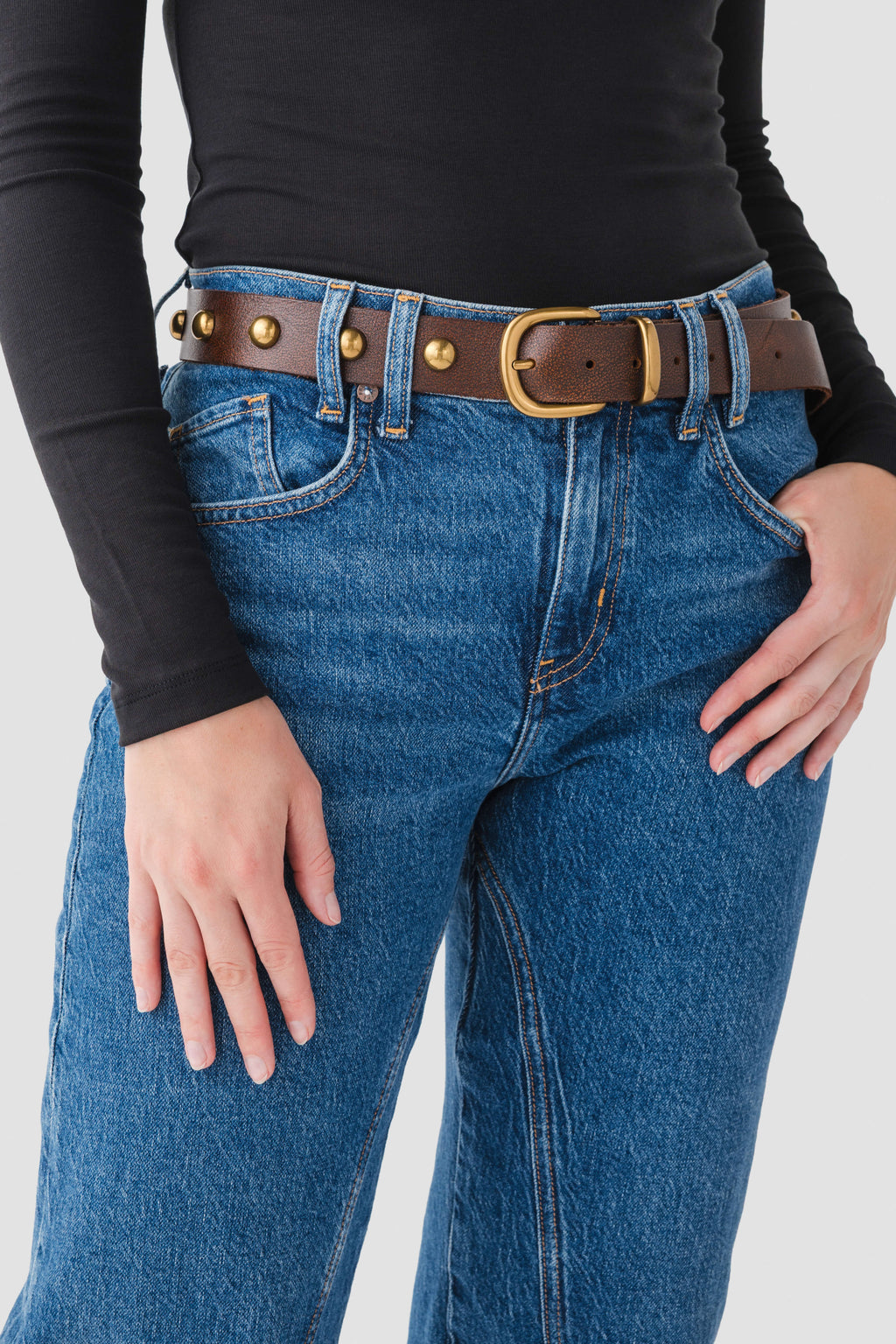 Cognac leather stud belt with gold grommets and tan buckle on blue jeans