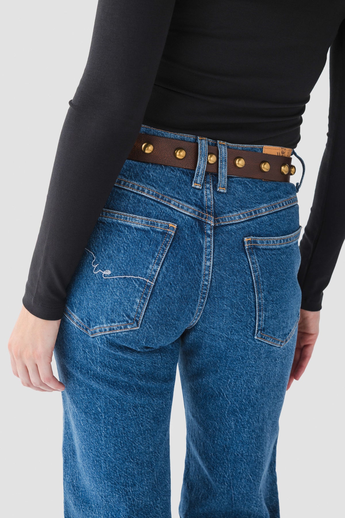 Cognac belt with gold studs and striped keeper straps on blue jeans