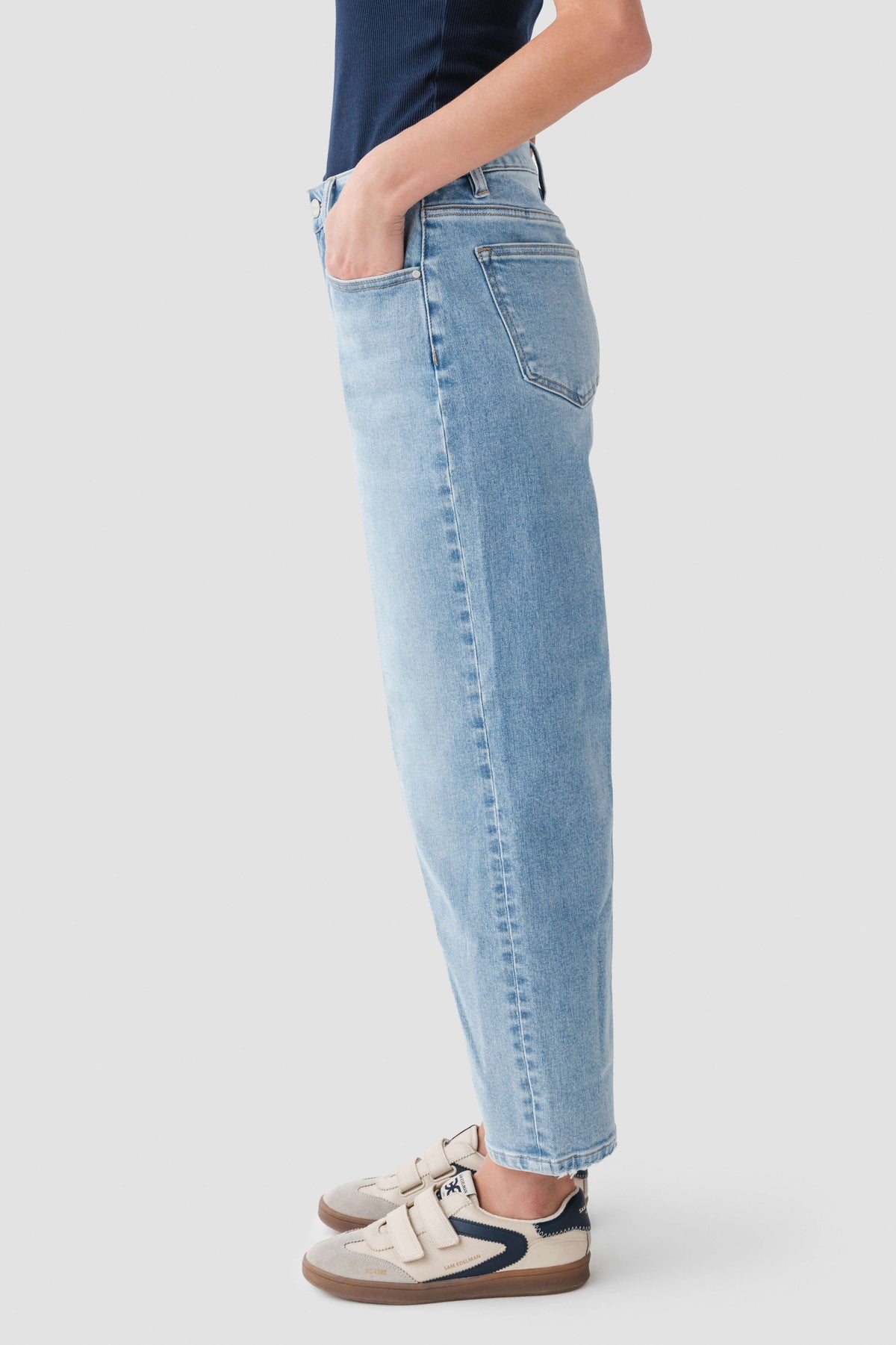 Medium wash denim barrel jeans with belt loops and front patch pockets, side view.