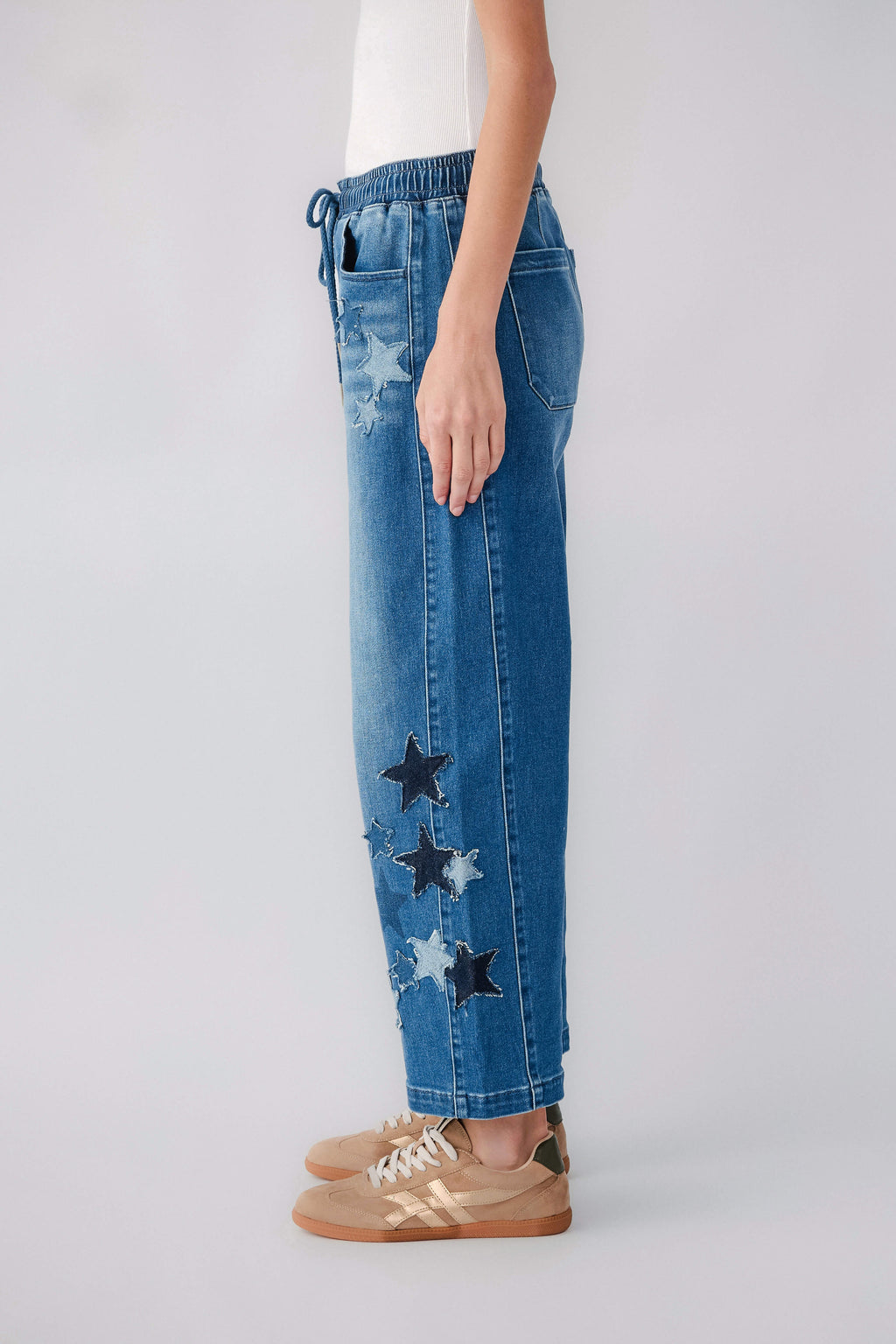 Women's blue barrel jeans, pull-on drawstring waist, side star graphics and distressed patches