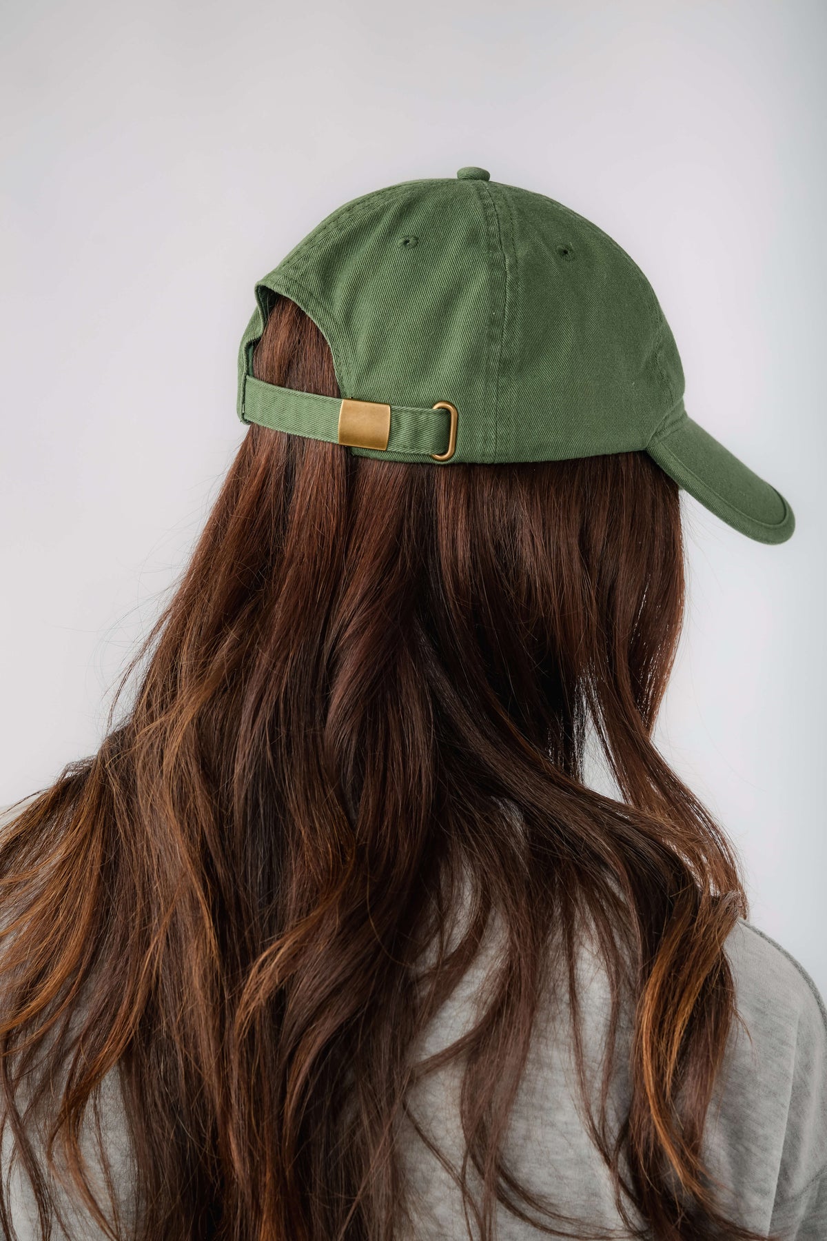 Green cap with adjustable back strap and gold buckle