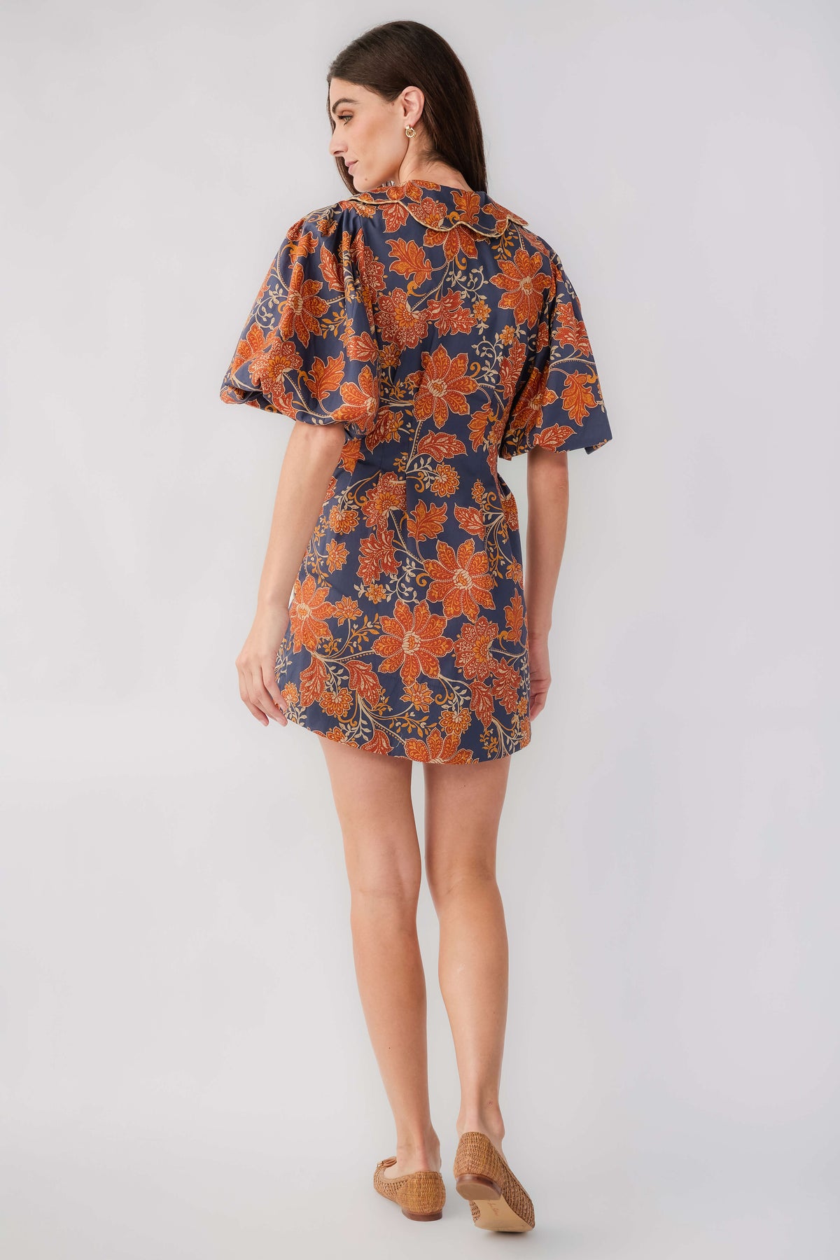 Back view of floral printed short dress in dark navy with rust, flutter sleeves