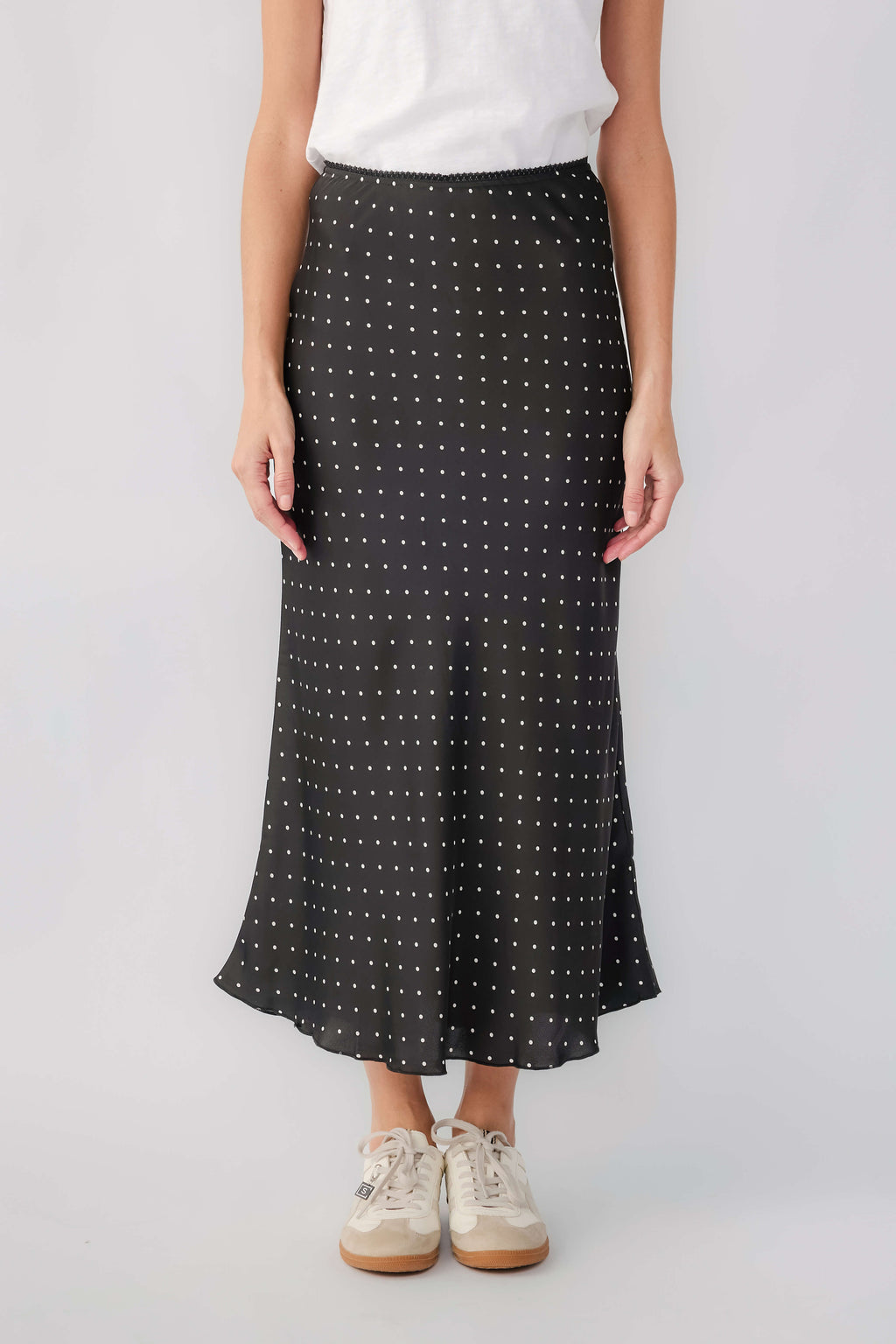 Black satin midi skirt with small white polka dots and flowy hem