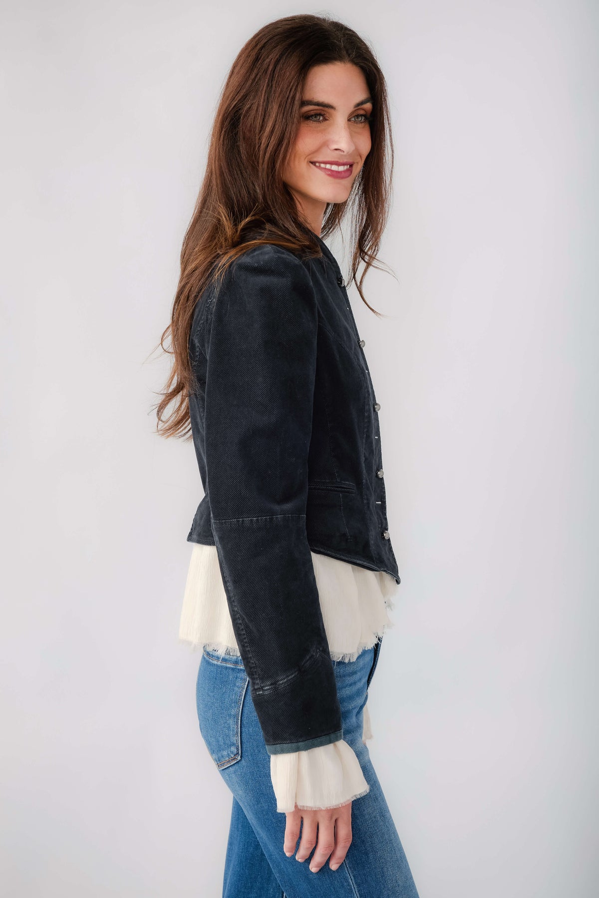 Black denim blazer side profile with button placket and white ruffled hem