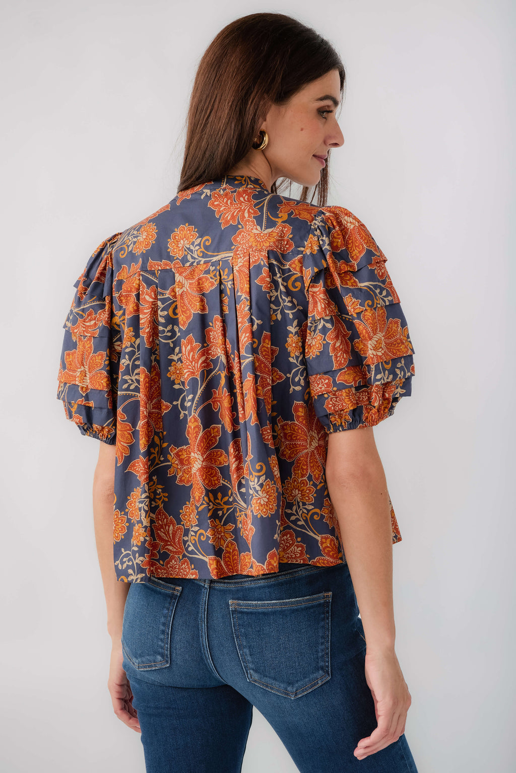 Back view of floral short-sleeve blouse in dark navy with rust pattern and puff sleeves
