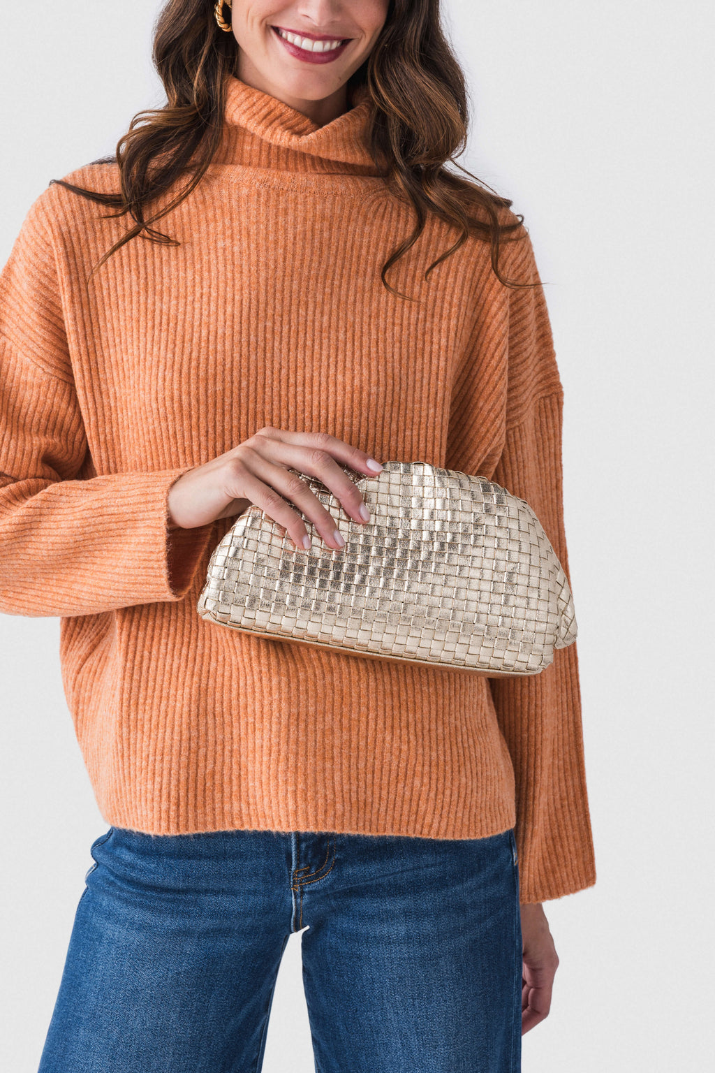 Gold woven frame clutch held in hand, braided chain strap and curved frame.