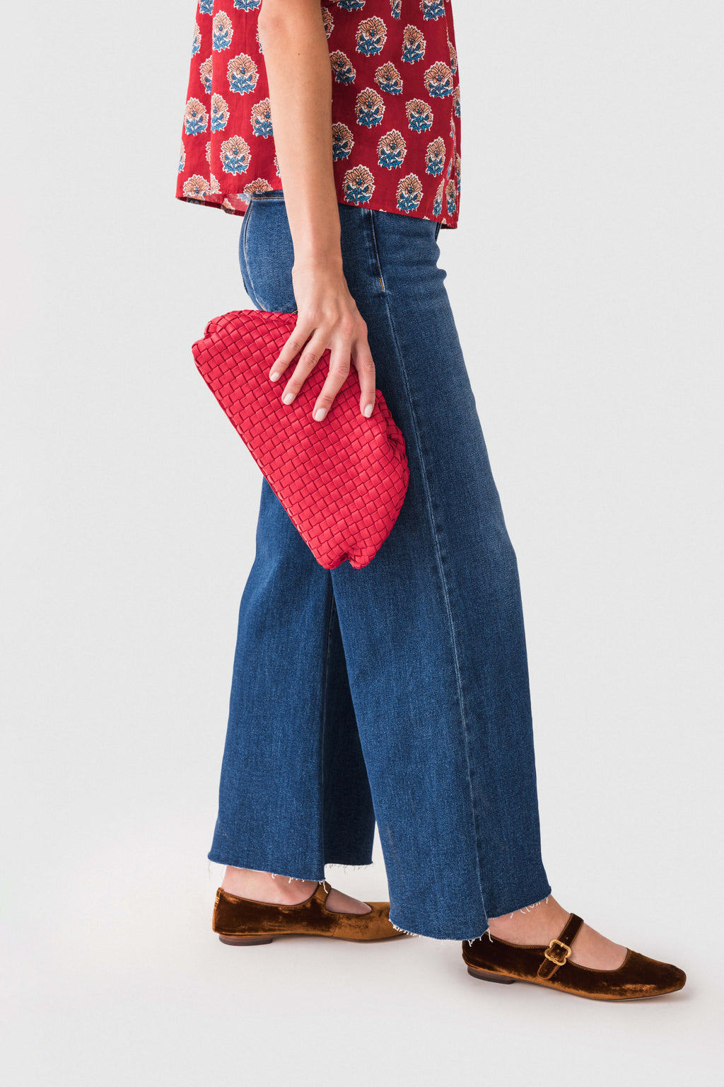 Red woven frame clutch held at side, braided chain strap and woven texture.