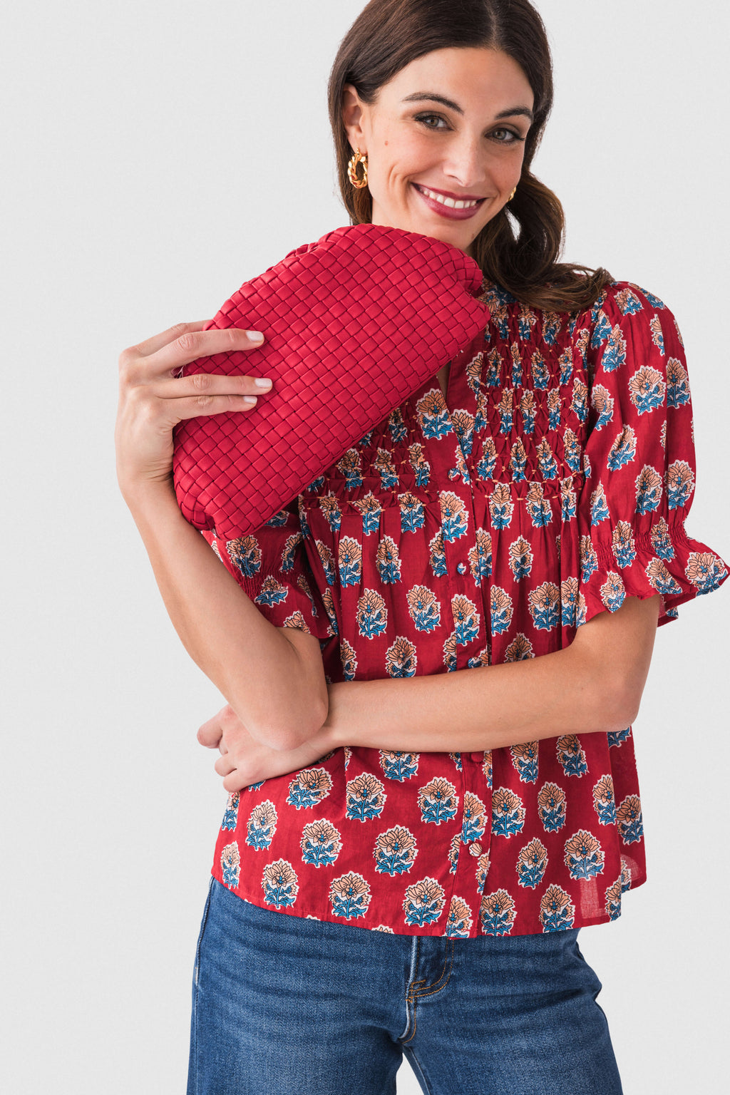 Red woven frame clutch held close, braided chain strap and curved woven body.
