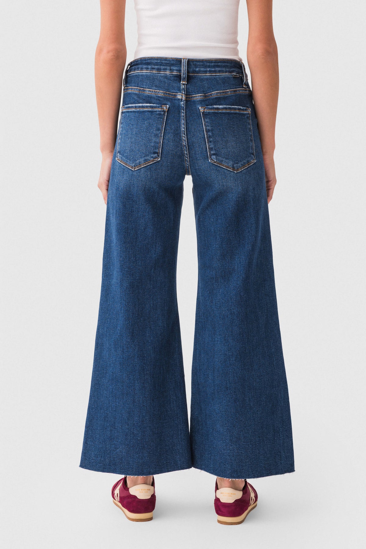 Back view of dark blue raw-hem palazzo jeans with stitched pockets and wide legs