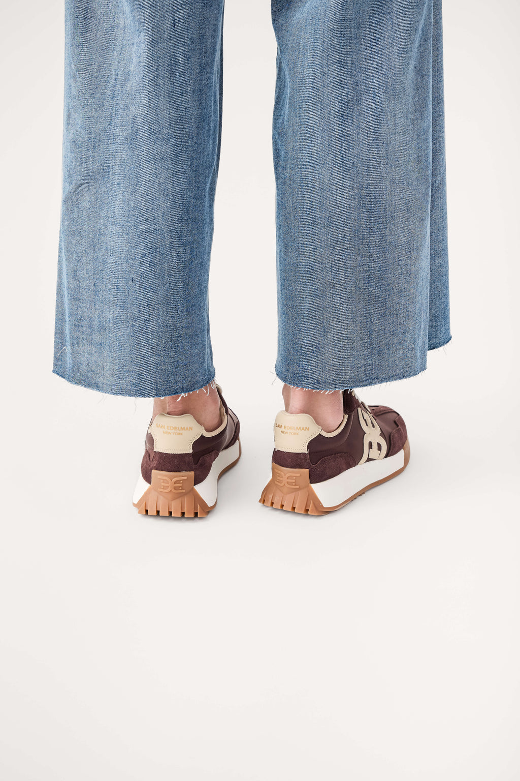 Brown lace-up sneakers with tan treaded sole and rear logo patch
