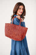 Rust woven tote bag held by wide top handles