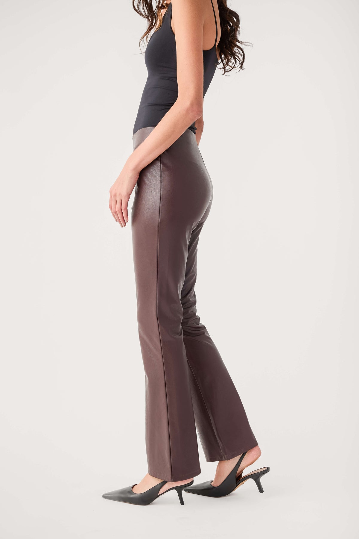Dark taupe-brown faux leather flare pants, side profile with smooth sheen