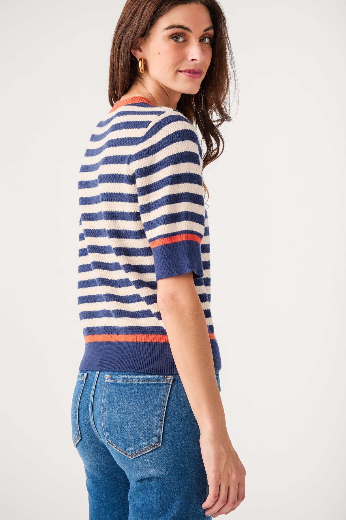 Navy and cream striped knit top with crew neck and orange-red stripe detail; side view