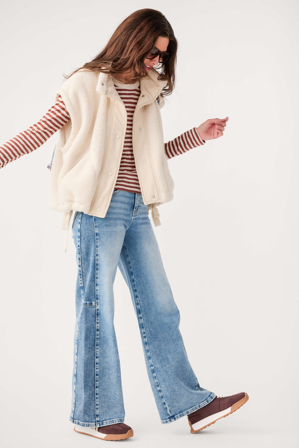 Cream fleece vest with button front and high collar, worn over striped long sleeves.