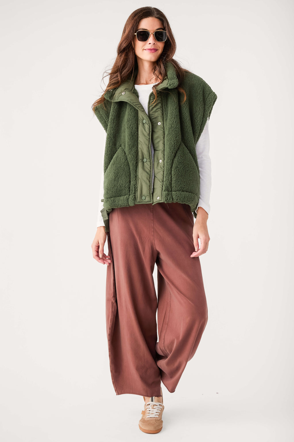Dark green fleece vest with snap buttons and stand collar, styled over a white shirt.