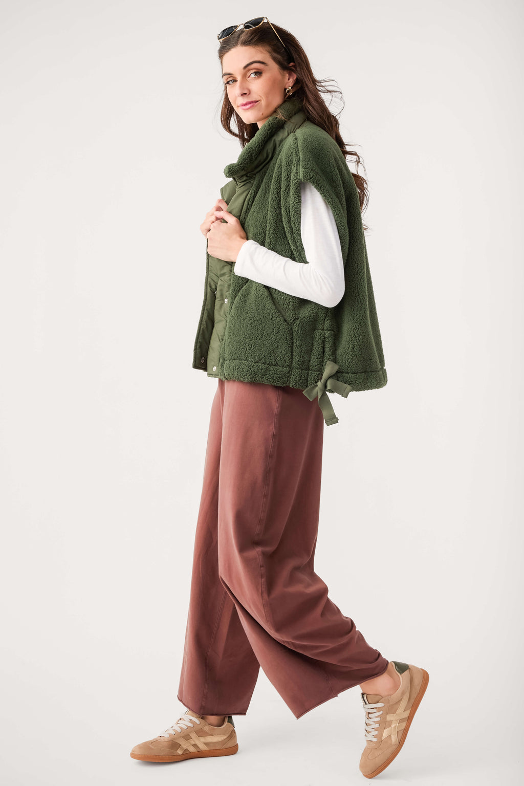 Ivy green fleece vest with button front and stand collar, model wearing it over long sleeves.