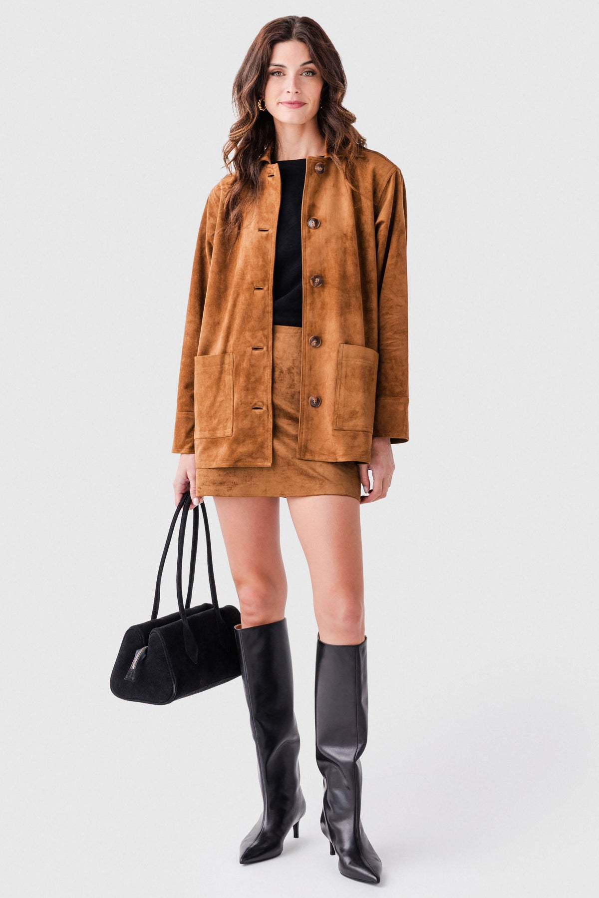 Black leather knee-high boots on model, pull-on silhouette with slim heels.