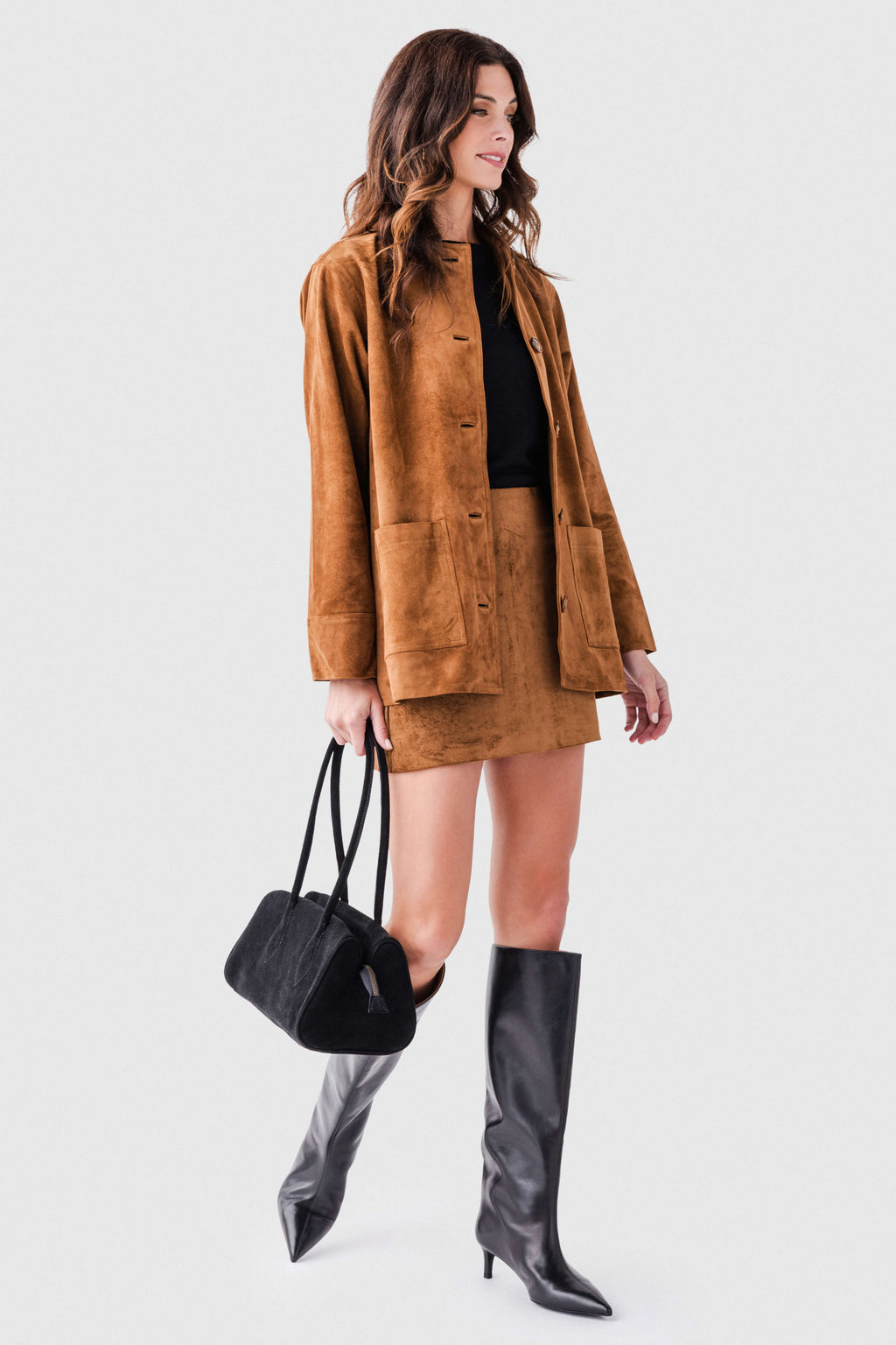 Black leather knee-high boots on model, pointed toe and slim kitten heel.