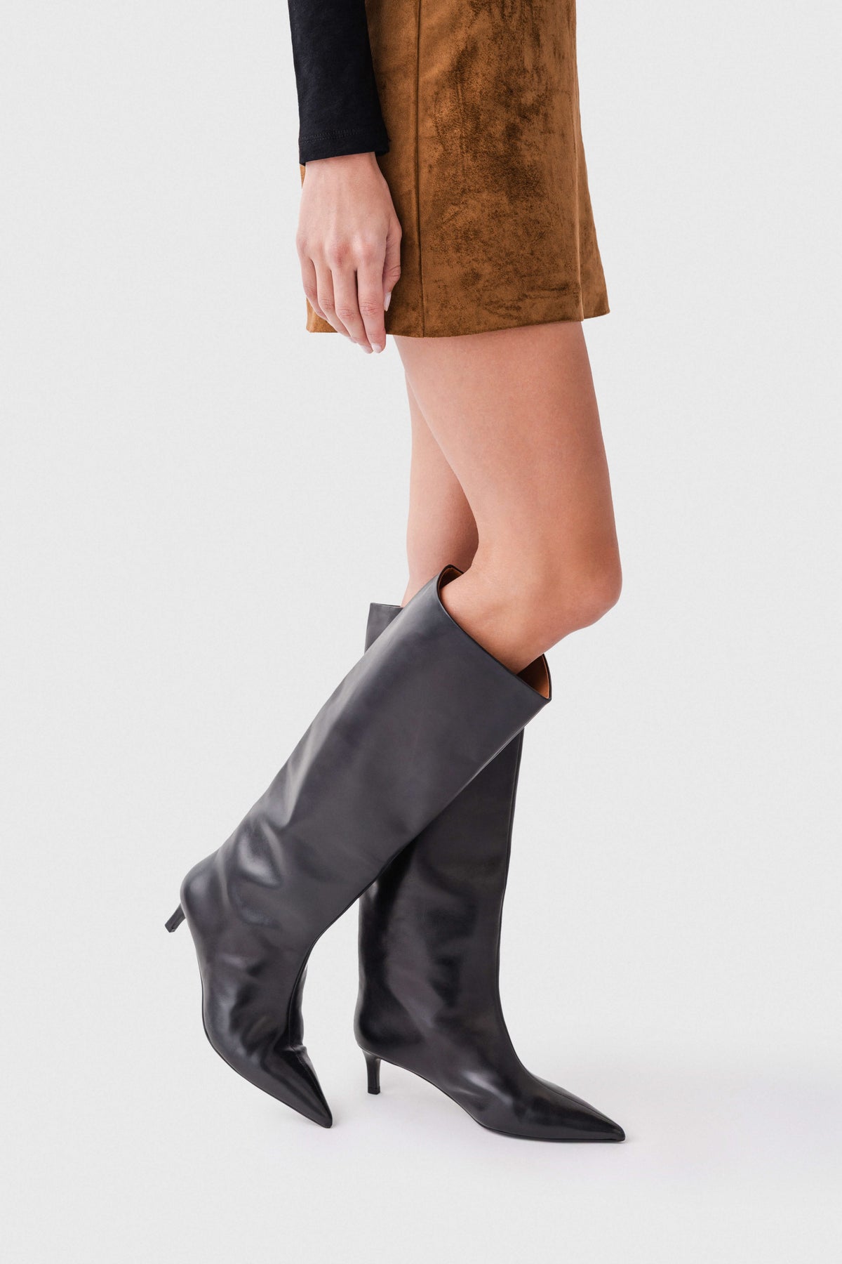 Black leather knee-high boots, angled view showing pointed toe and thin heel.
