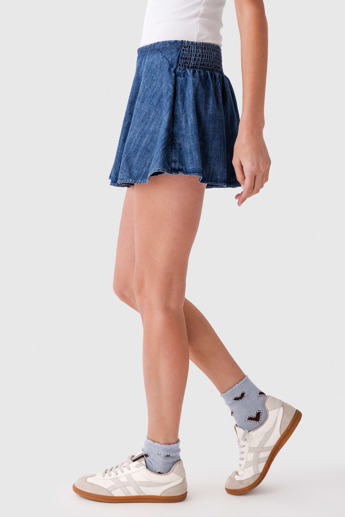 Blue denim skort side view with elastic waist and flared hem, above-knee