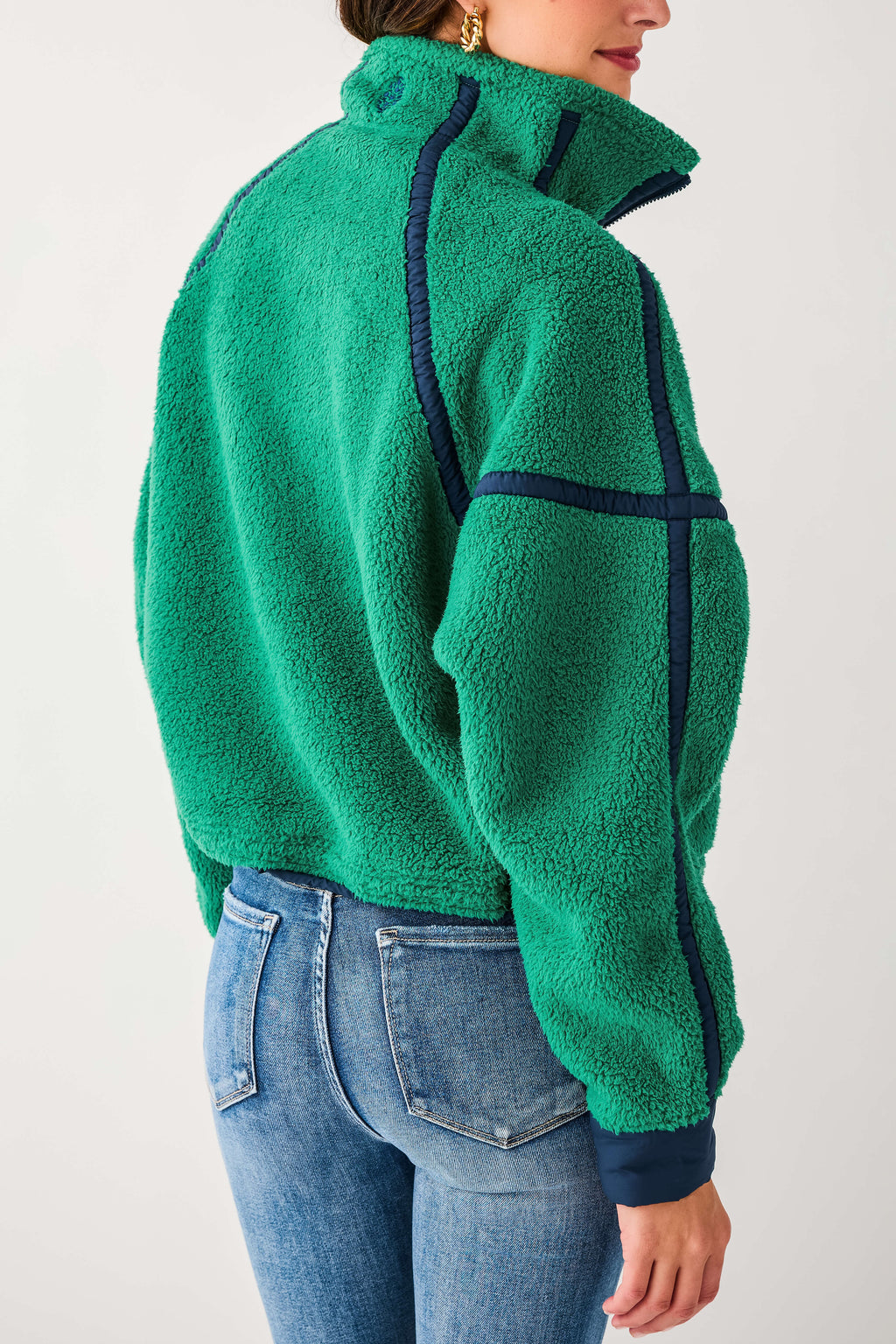 Side view of green 1/2 zip fleece with dark paneling and textured fleece