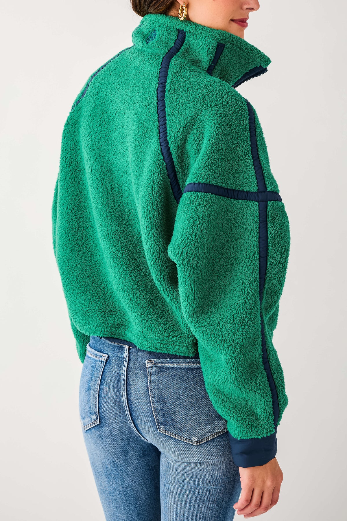 Side view of green 1/2 zip fleece with dark paneling and textured fleece