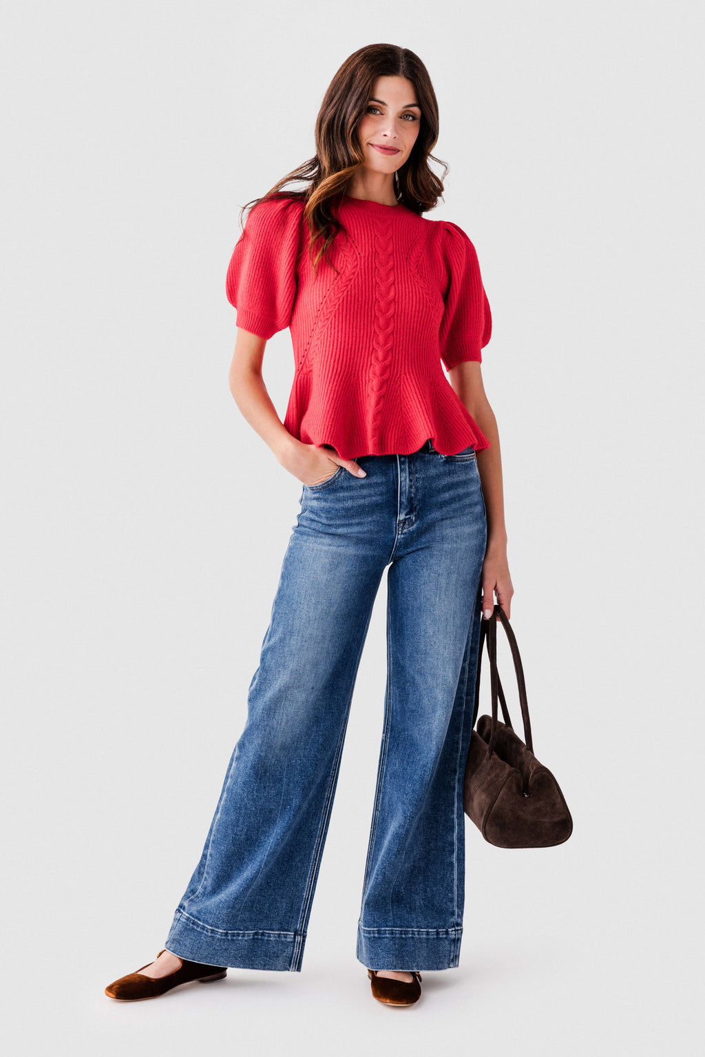 Red flared knit peplum top with puff sleeves and cable knit front detail, worn with jeans.