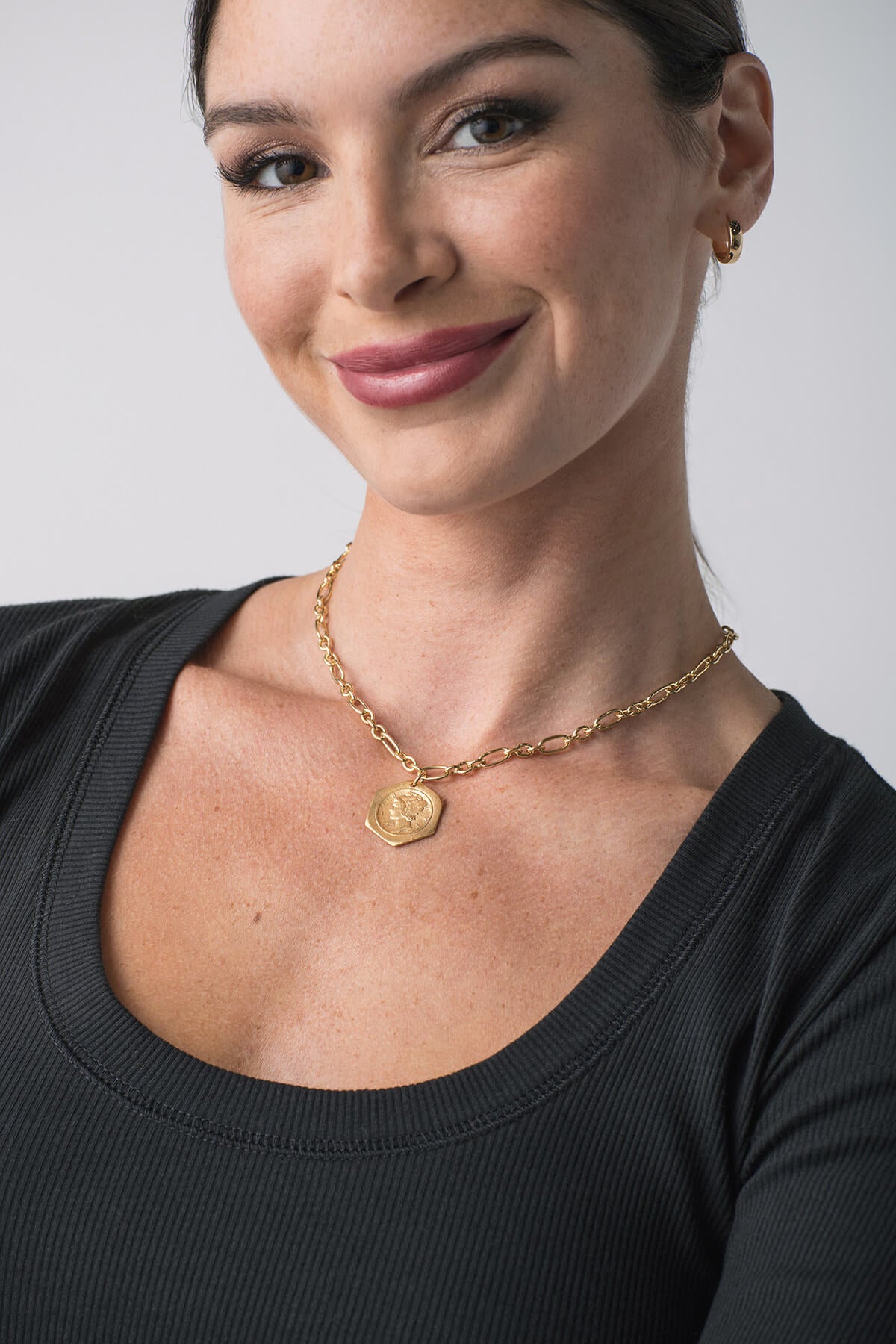 Gold chain necklace with hexagon pendant worn on neckline