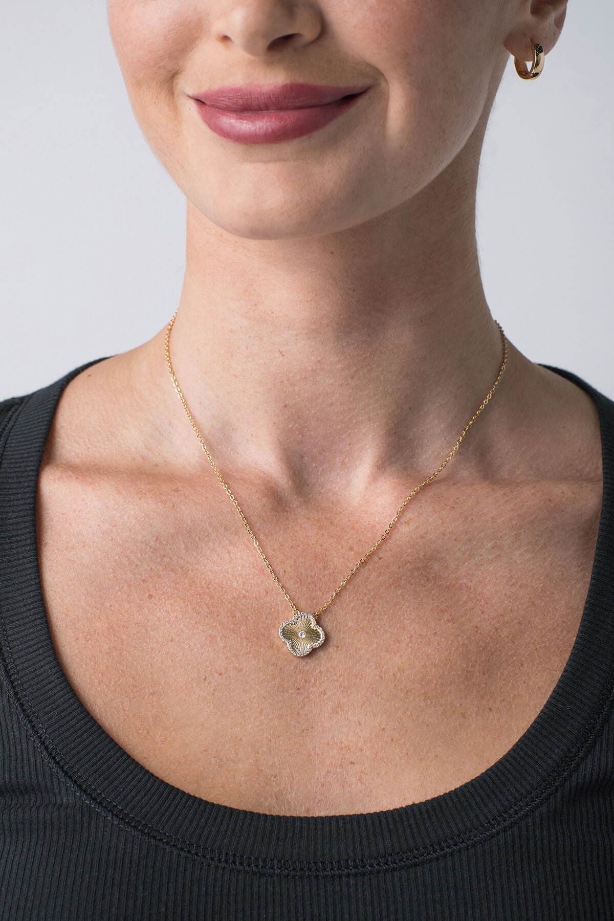 Gold flower icon pendant necklace with blue crystal accents and small circular center