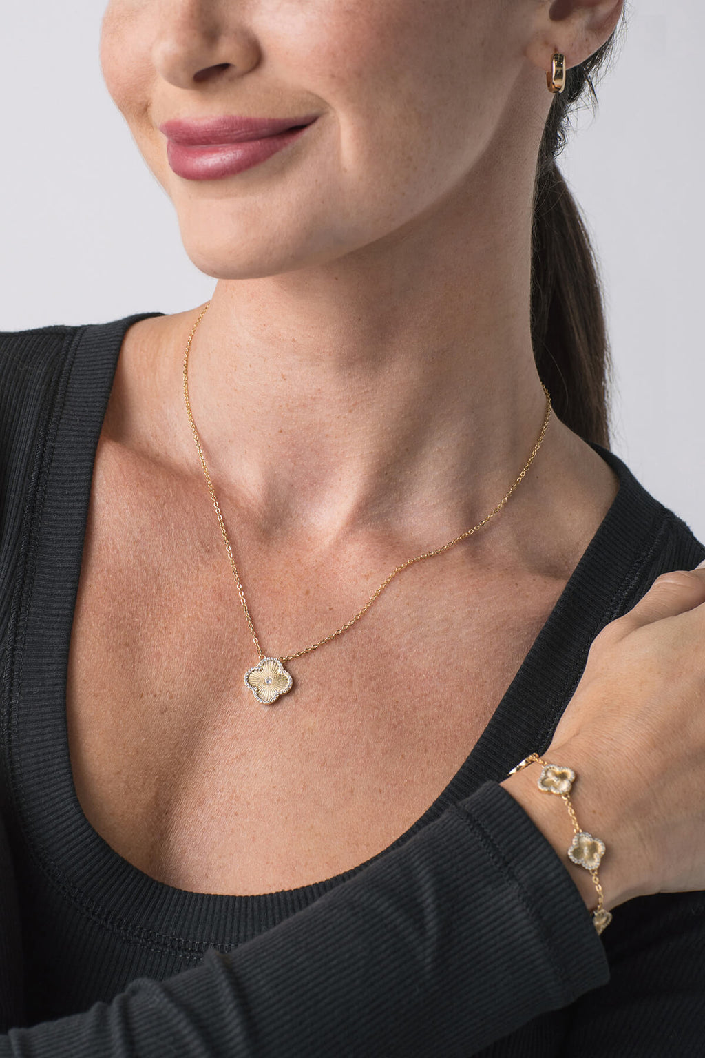 Gold icon pendant necklace with blue crystal flower charm; matching bracelet shown