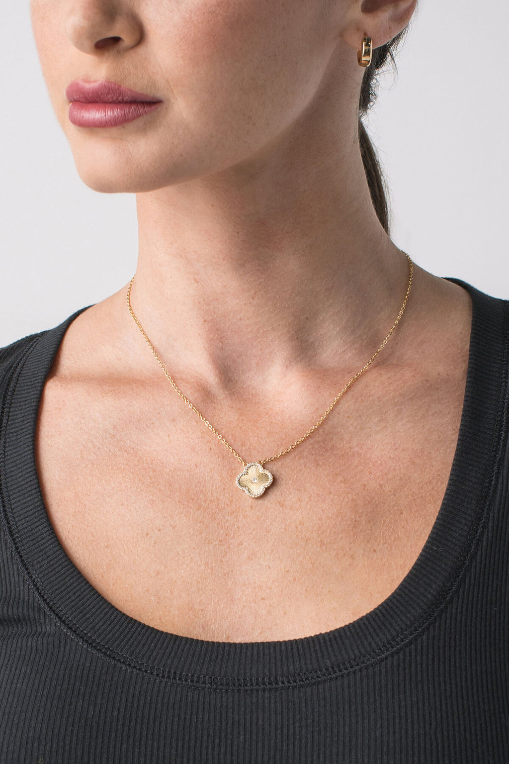 Gold flower icon pendant necklace with blue crystal accents, worn at the neckline