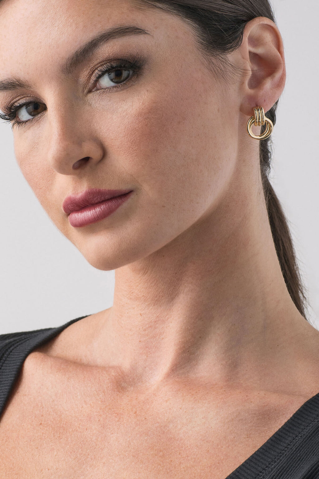 Gold mini knocker hoop earrings on ear, ridged top with circular ring