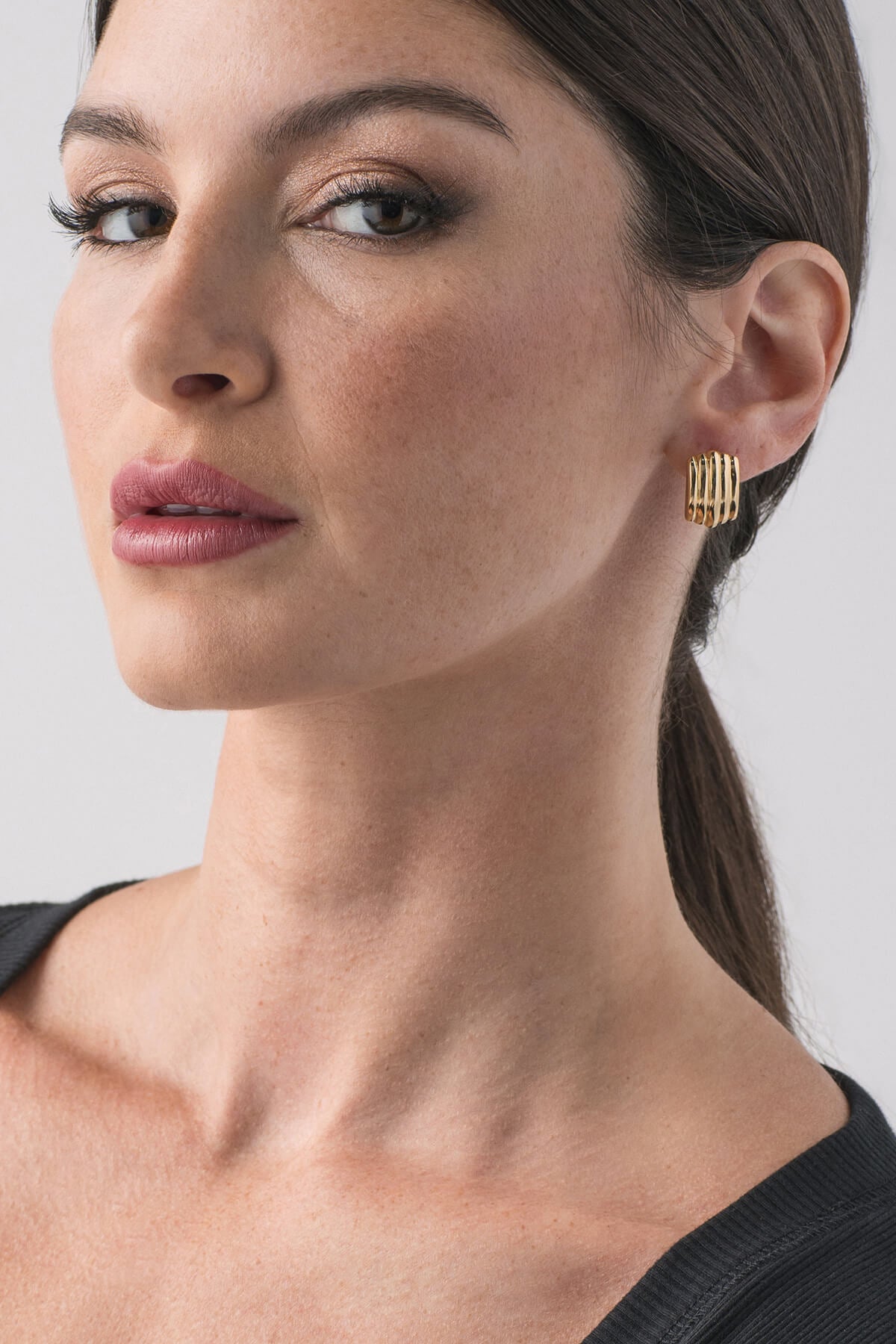 Gold textured hoop earrings with vertical ridges on model’s ear