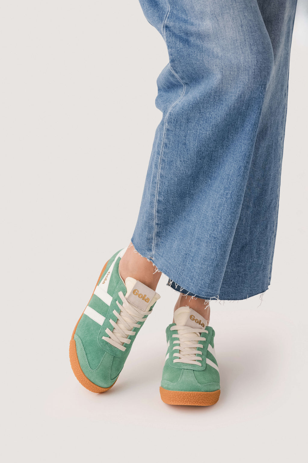Green low-top sneakers with white stripes, lace-up front, tan rubber sole
