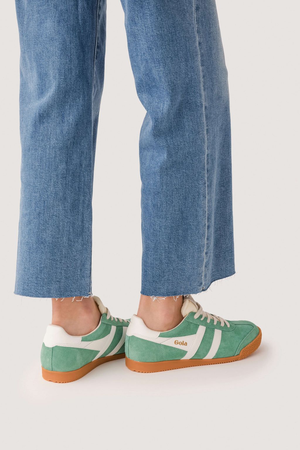 Green lace-up sneakers with white stripes and tan gum sole, side view