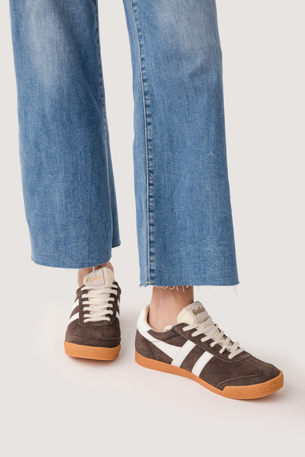 Brown low-top sneakers with white stripes and gum sole, showing side profile.