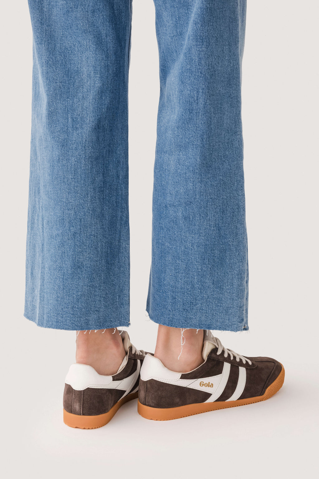 Brown low-top sneakers with white stripes and gum sole, rear view.
