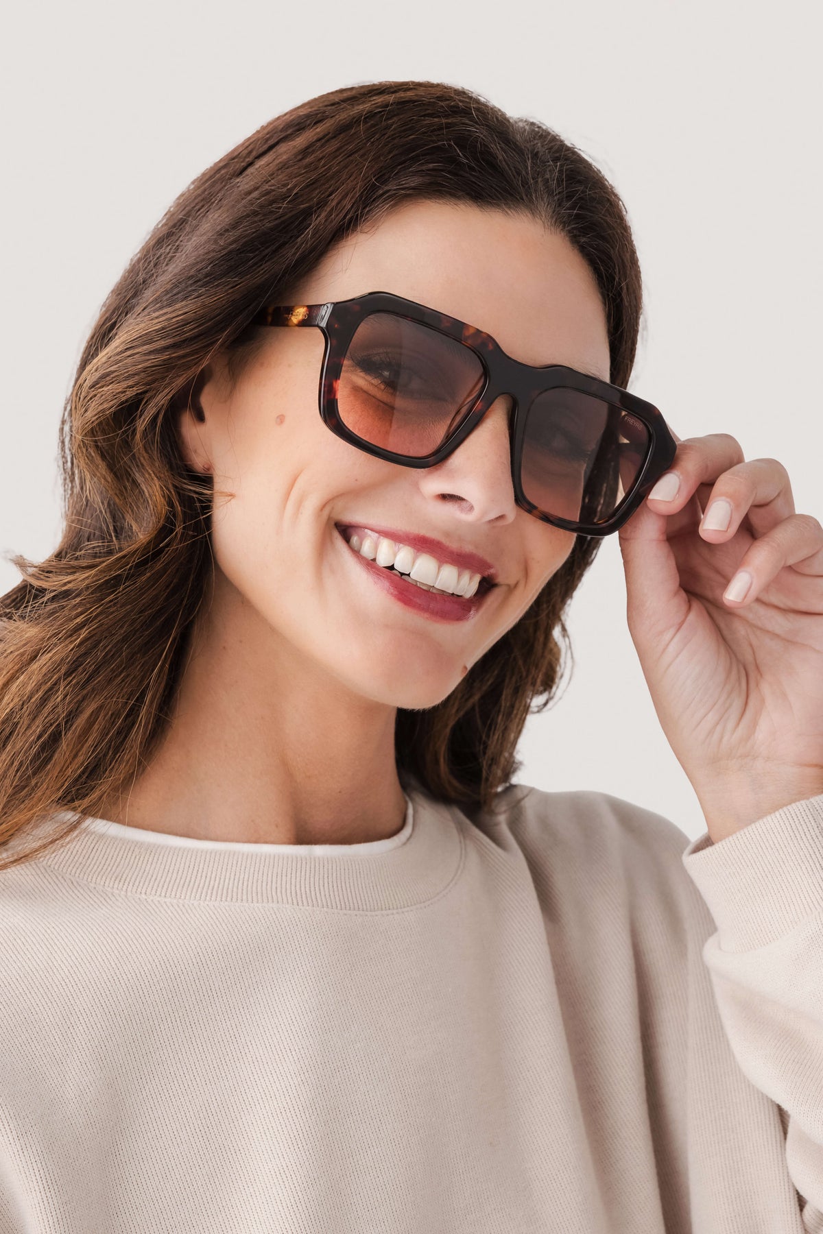 Rectangular acetate sunglasses, dark tortoise frame with dark lenses, hand on temple