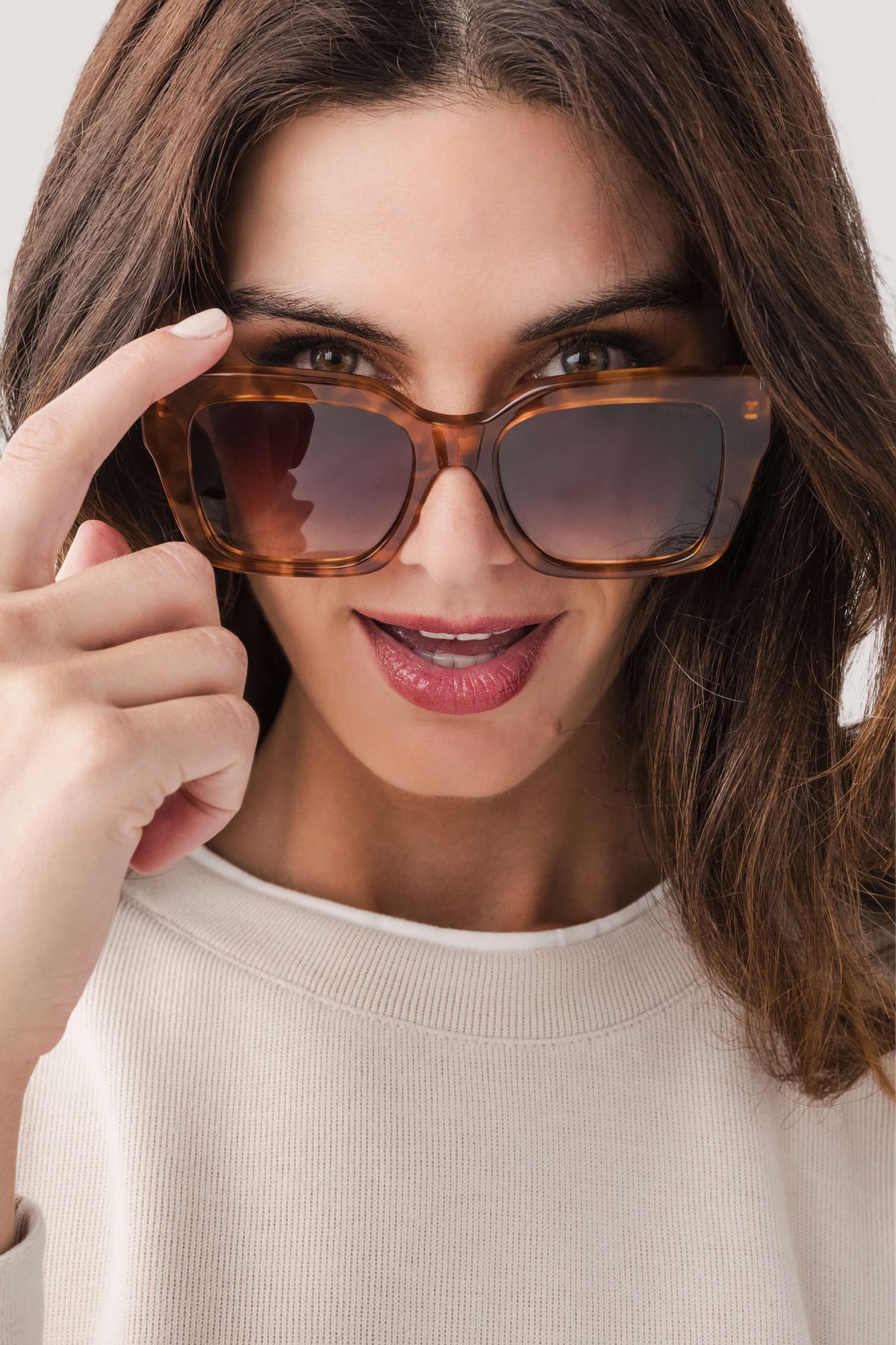 Oversized brown acetate sunglasses with dark tinted lenses, square frames held near face
