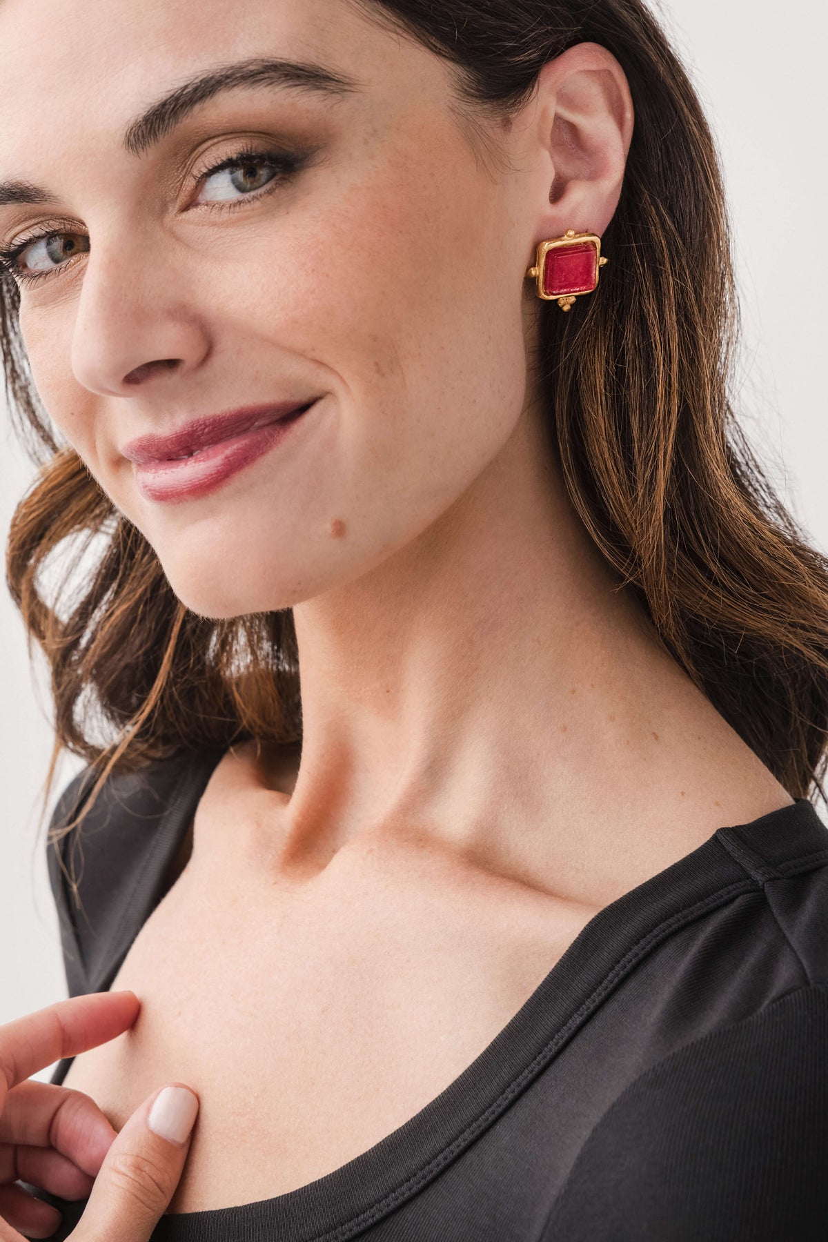 Gold square stud earrings with red glass center, on pierced ear