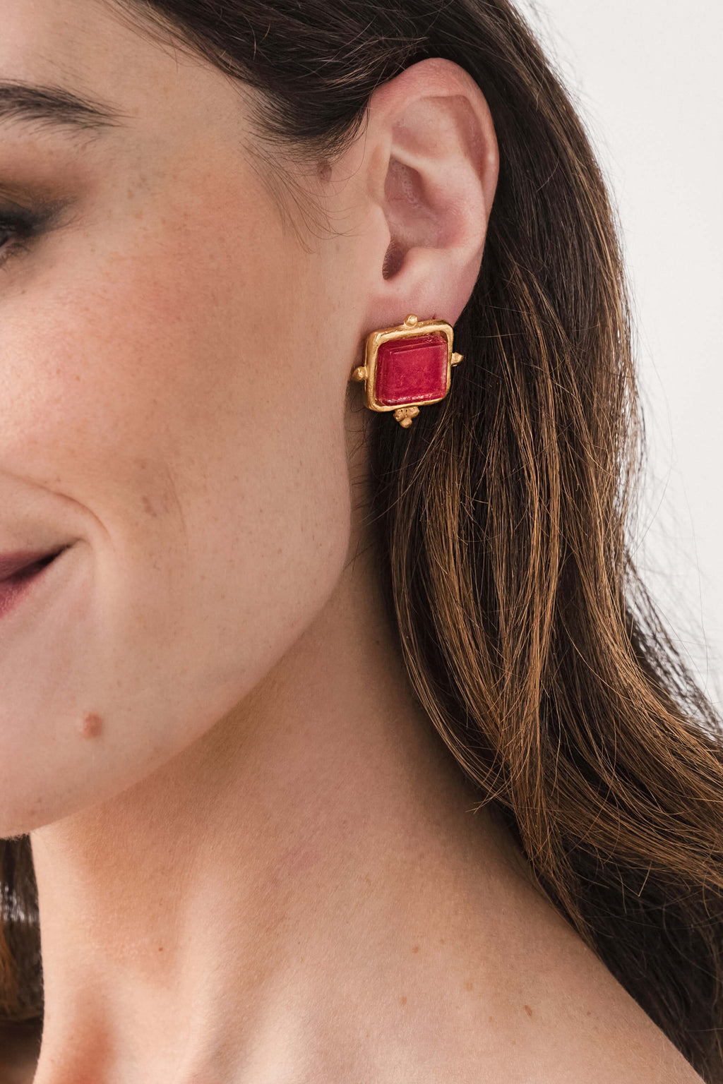 Gold square red glass stud earrings, side view on pierced ear