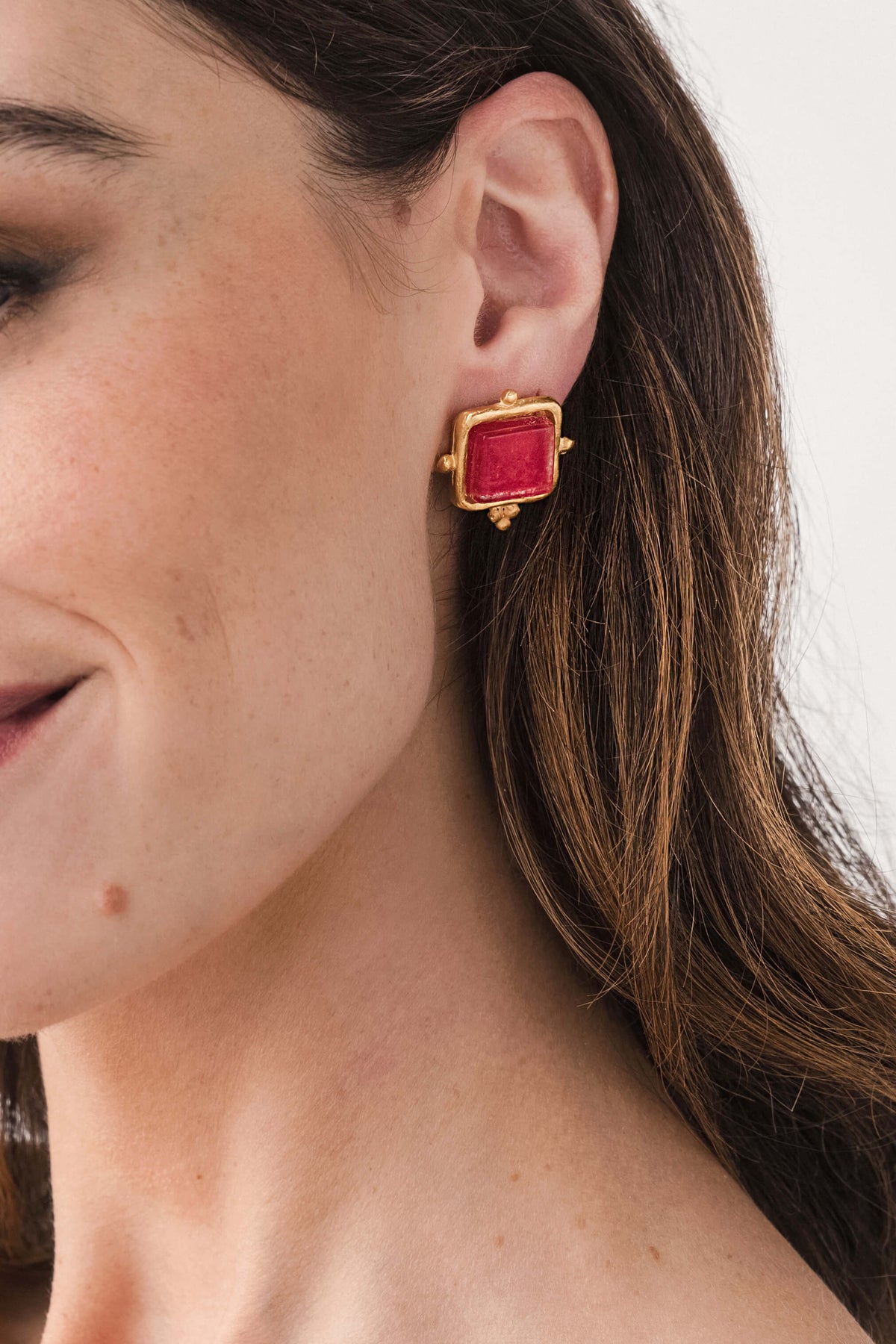 Gold square red glass stud earrings, side view on pierced ear