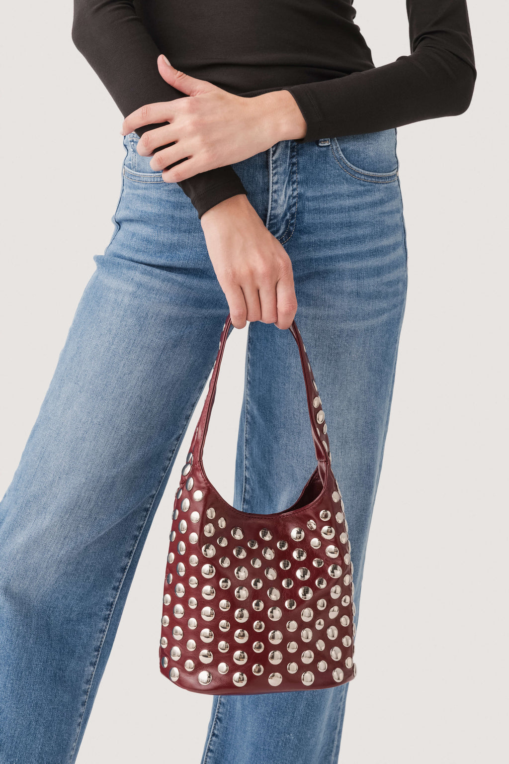 Deep red studded hobo bag with silver-tone metal studs and braided strap handles