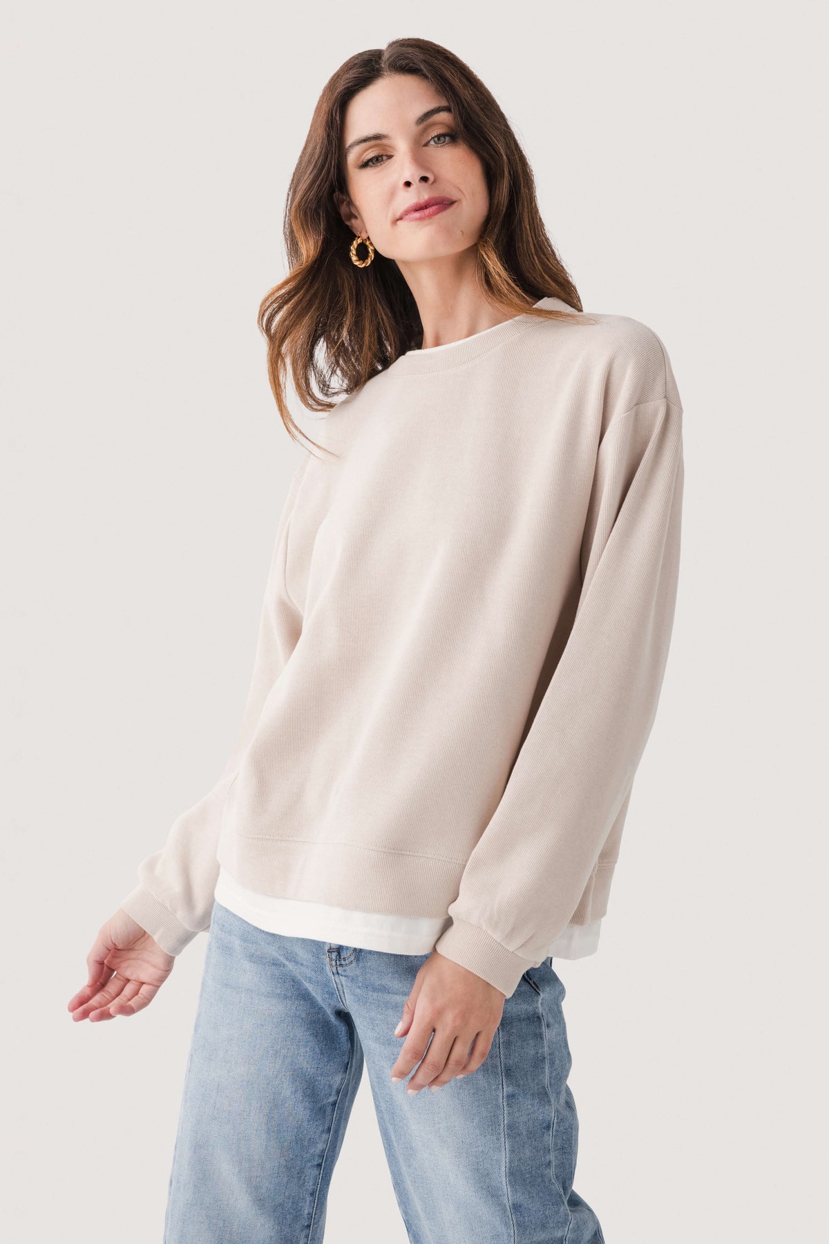 Light beige crewneck pullover sweater, angled front view with ribbed cuffs