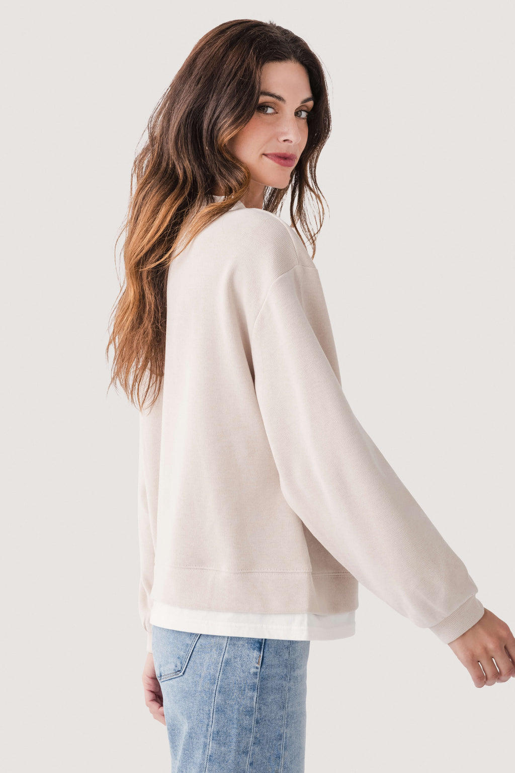 Light beige crewneck pullover sweater shown from the side with long sleeves
