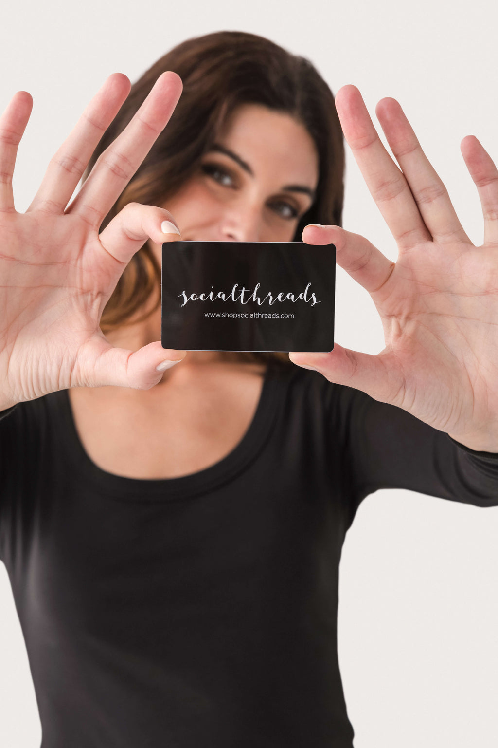 Gift card in front of face; black card with white printed logo
