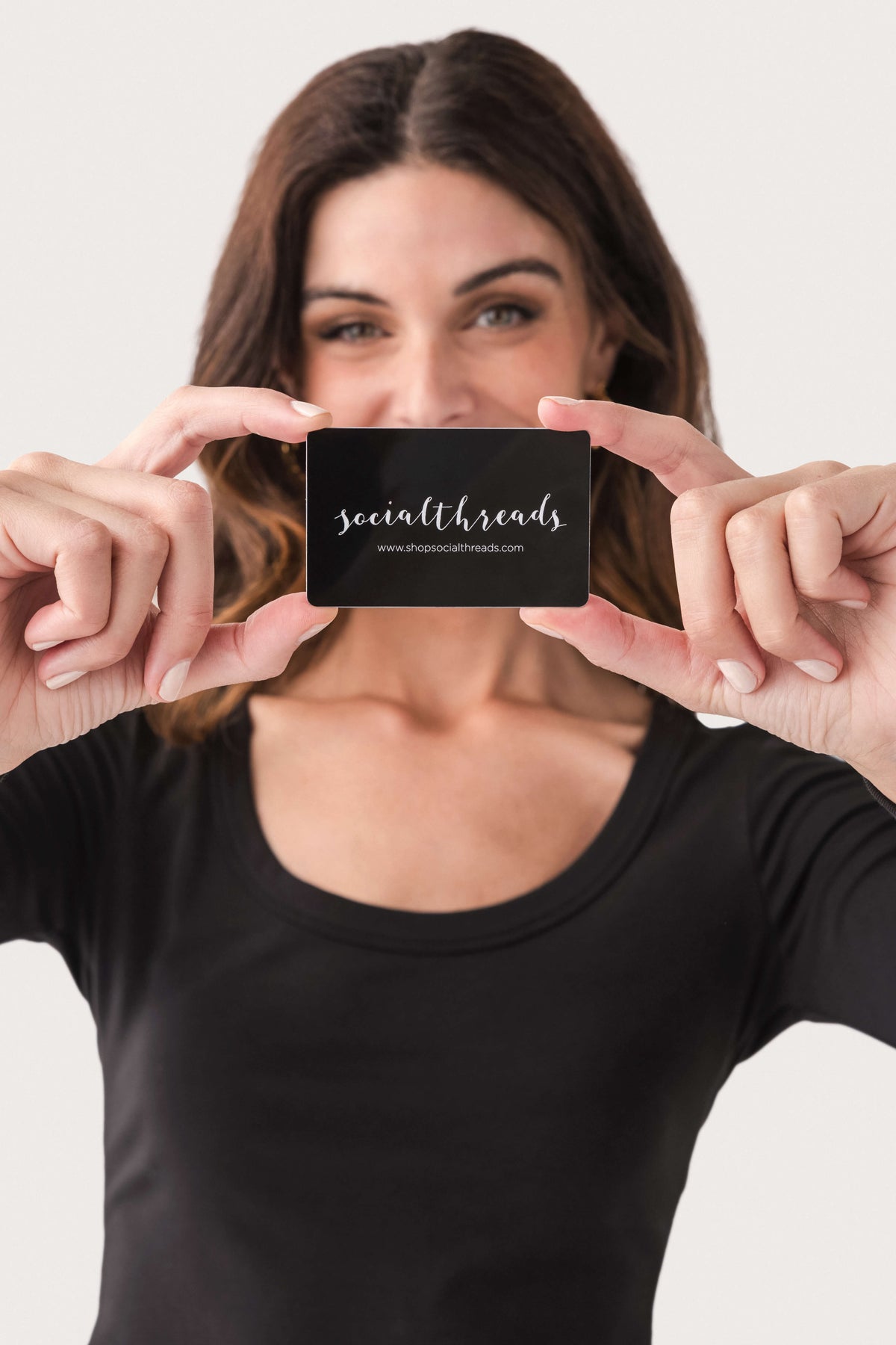 Gift card held toward camera; black card with white logo text
