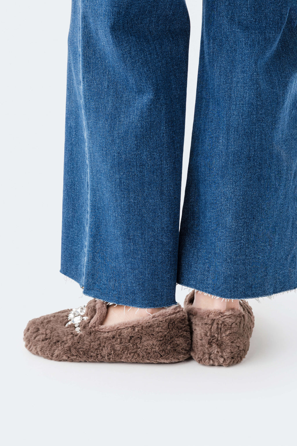 Brown plush loafer slippers with silver floral jewel detail at the toe opening.