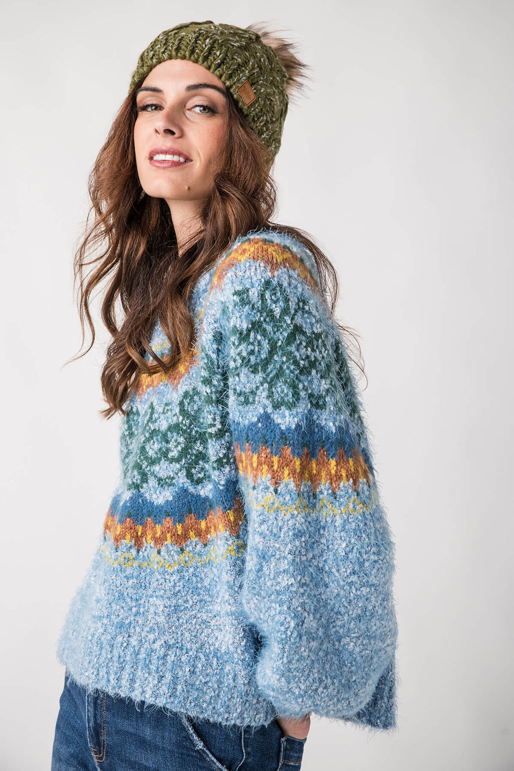 Olive cable-knit pom hat with ribbed cuff and fluffy top pom.