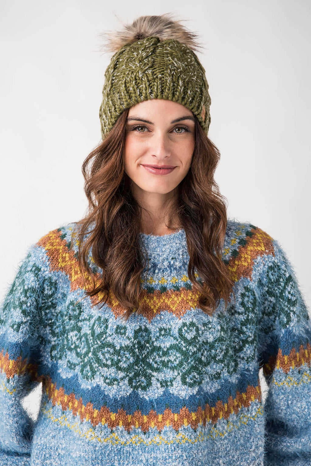 Olive cable-knit pom hat with ribbed cuff and chunky textured knit.